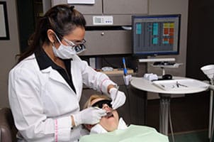 Image of Dr. Samarrae checking a patient's dental health.