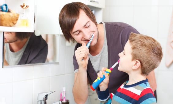 A father and son brush their teeth together