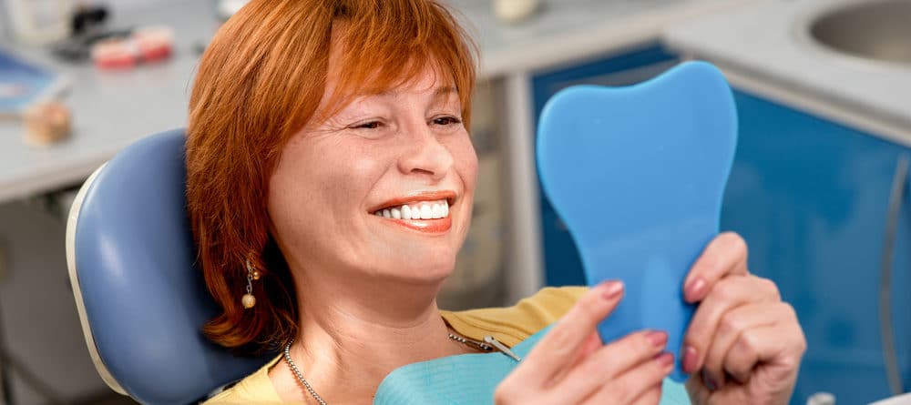 woman looking in the mirror at her new smile